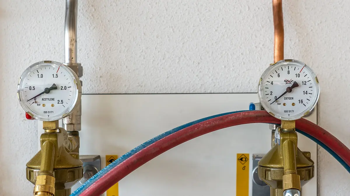 Two pressure gauges on copper pipes with red and blue hoses
