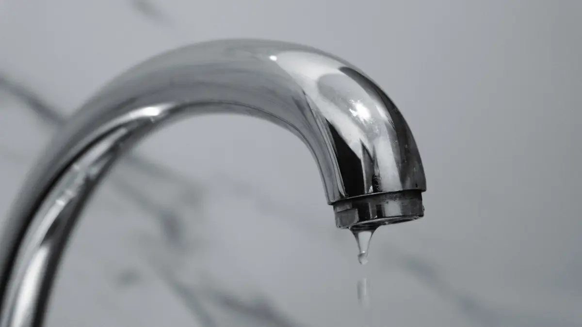 Chrome tap with water dripping from the spout