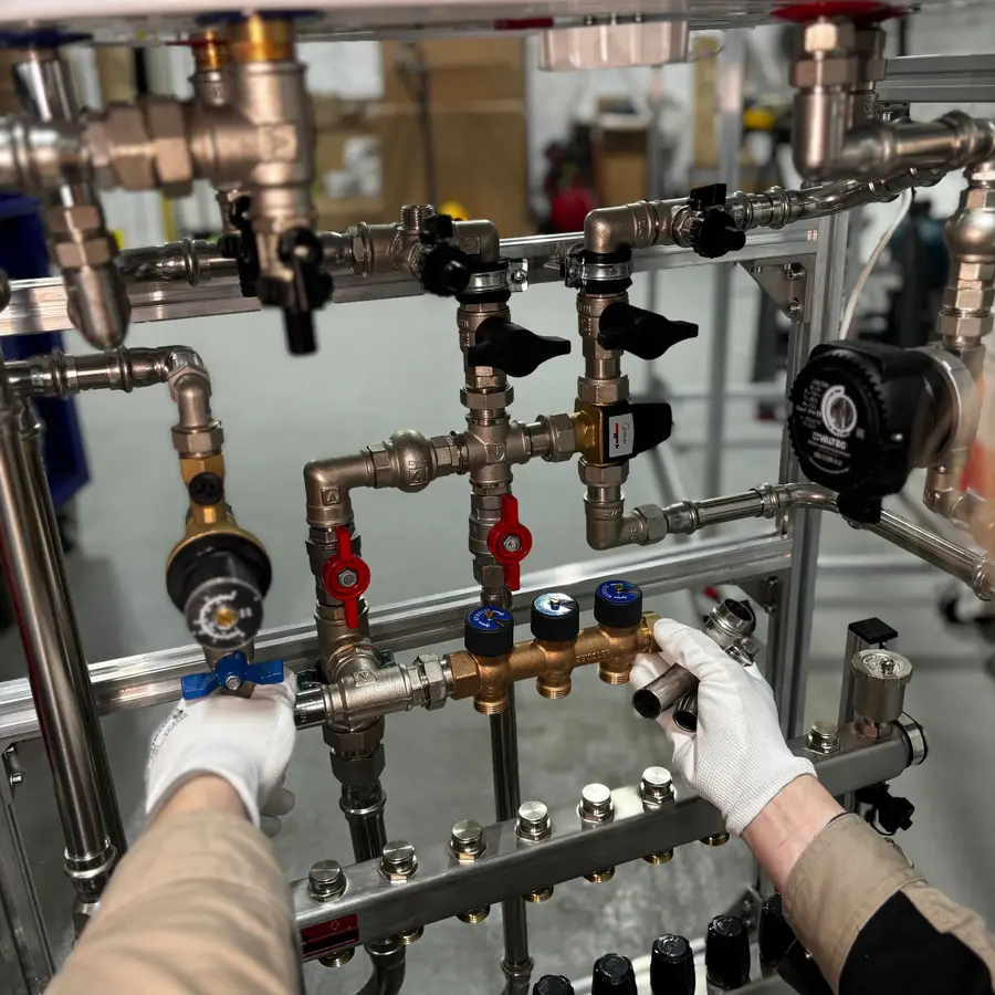 Gloved hands working on a heating manifold