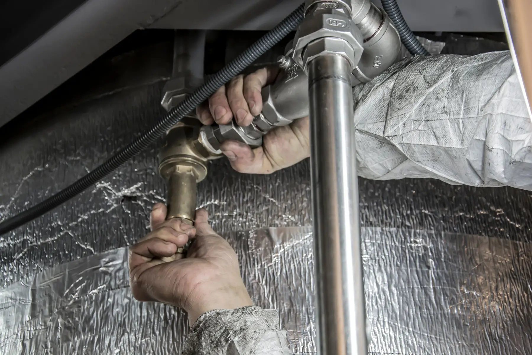 Plumber fitting pipework under a kitchen sink